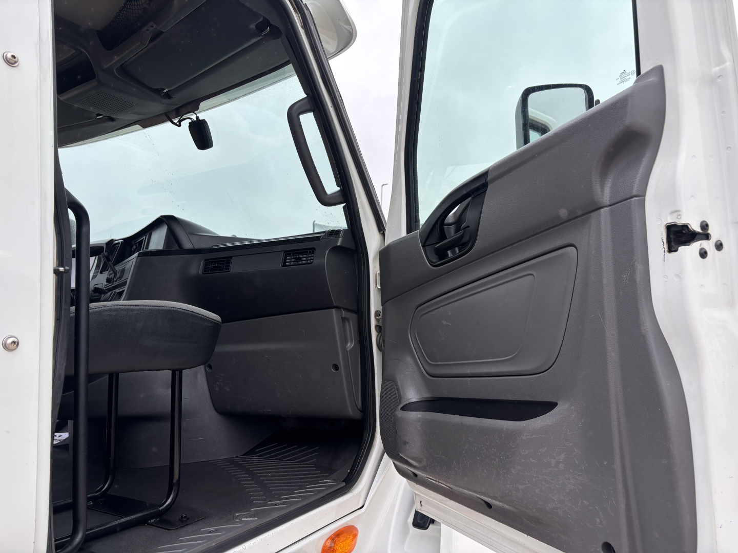 Truck cab interior view of a 2019 International LT Daycab, door open showing dashboard, steering wheel, and driver's seat; no visible labels or numbers readable in image.