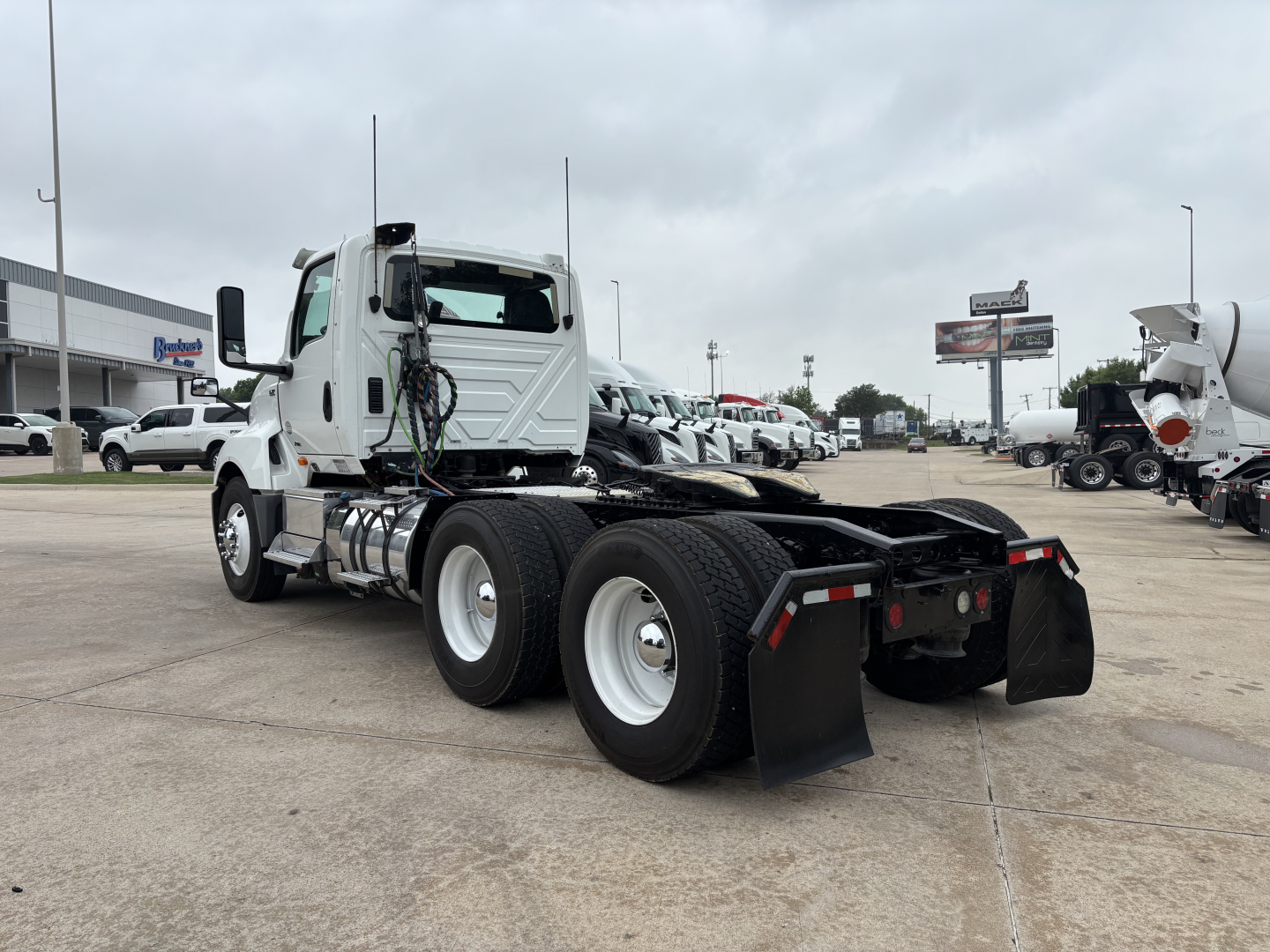 Truck chassis of a 2019 International LT daycab showing rear dual-axle configuration with mudflaps and fifth-wheel/rigid frame. Visible components include fuel tanks and exhaust piping near the cab.