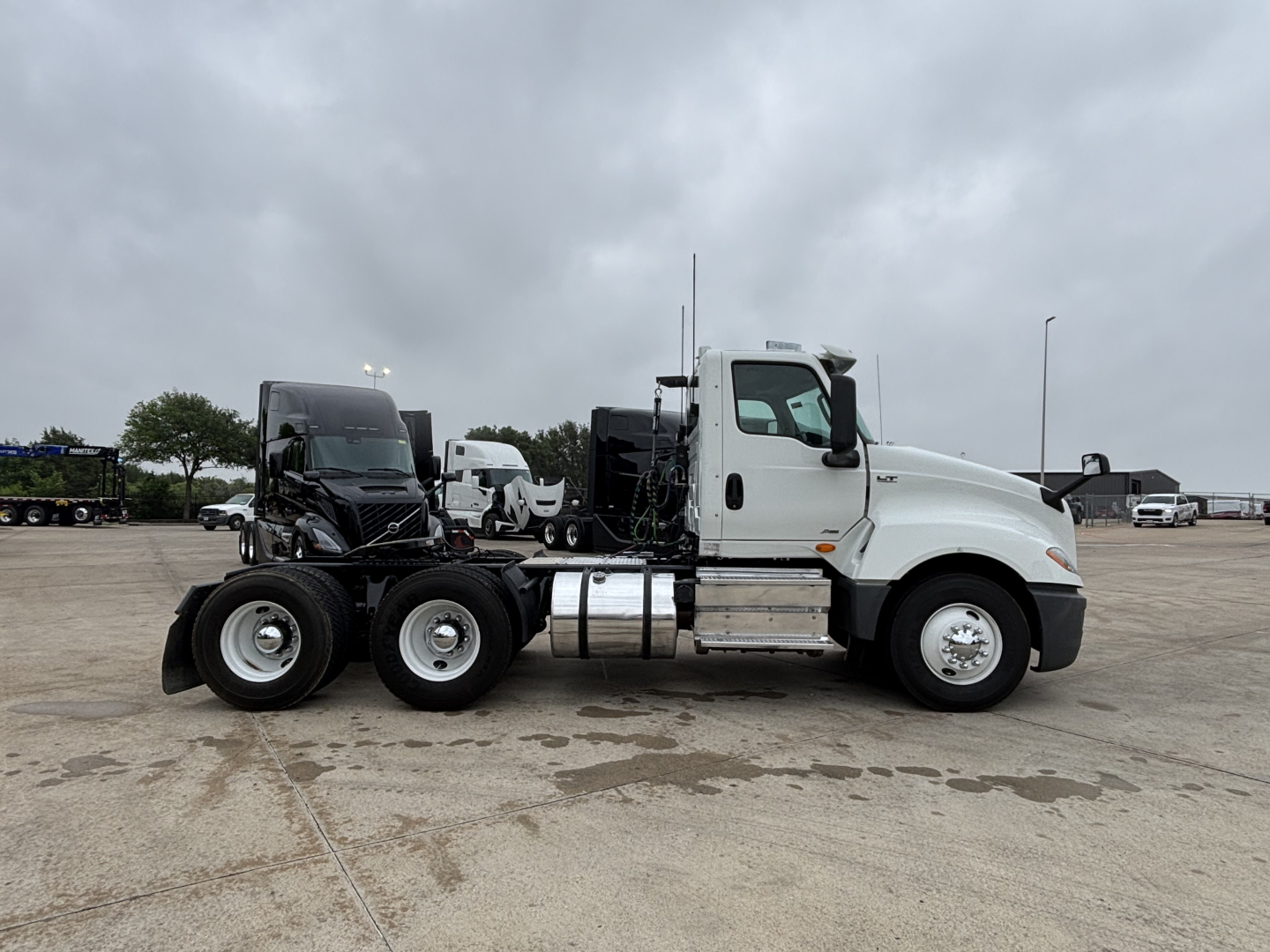 Truck side view showing a white 2019 International LT daycab with dual rear axles and a black sleeper cab trailer connection; no visible text on the truck body.