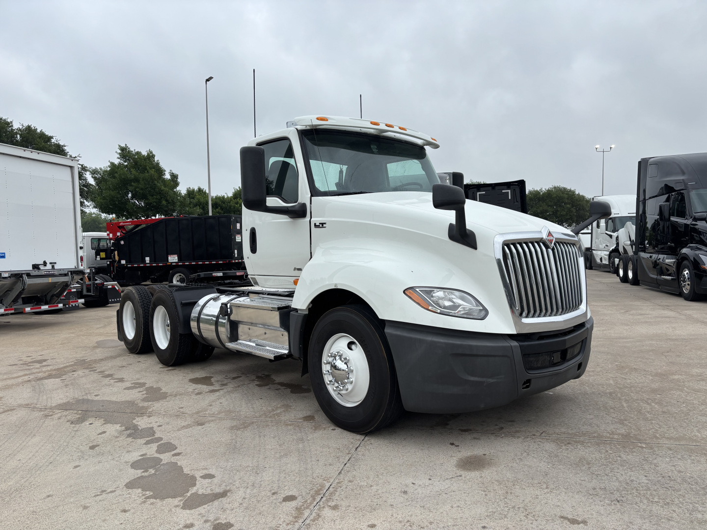 2019 International LT conventional daycab tractor showing front-left angle, with white cab, black bumper, and dual rear axles. Visible text includes International badge on grille and LT model near headlight, and chrome fuel tanks.