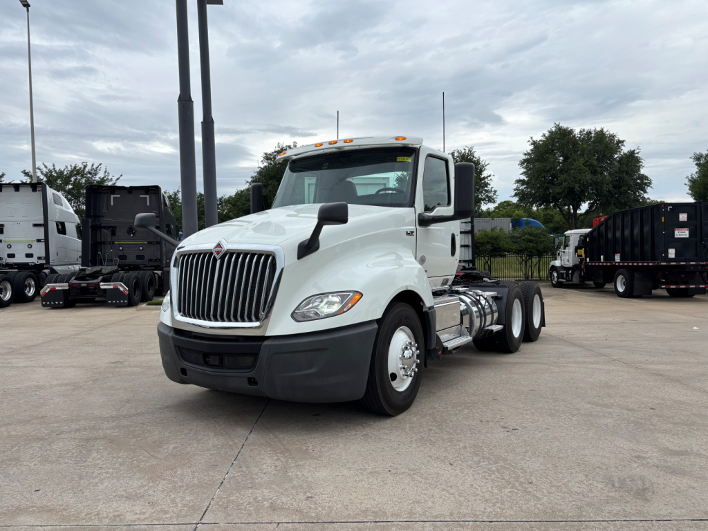 Truck cab showing International LT daycab chassis with front grille, dual rear axles, and white exterior.