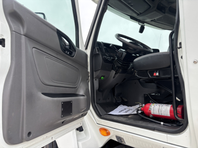 Cab interior of a 2019 International LT from the driver side, open door, steering wheel, dashboard, and a red fire extinguisher on the floor.