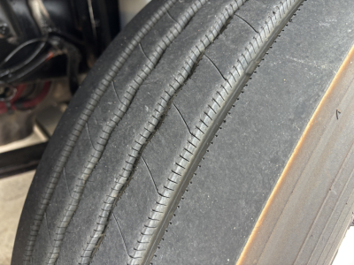 Tire tread and sidewall close-up showing highway-season tire on a truck wheel.