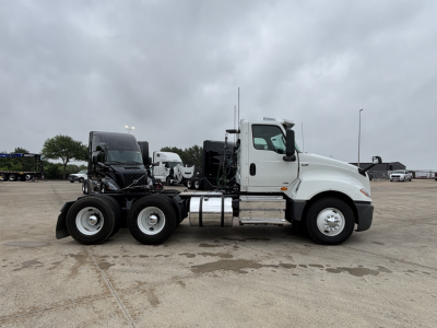 Truck side view showing a white 2019 International LT daycab with dual rear axles and a black sleeper cab trailer connection; no visible text on the truck body.