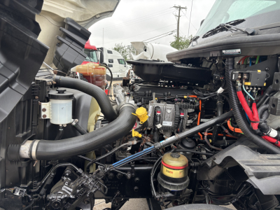 Engine bay of a 2019 International LT showing hoses, reservoirs, and engine components with visible yellow oil dipstick and coolant hoses.