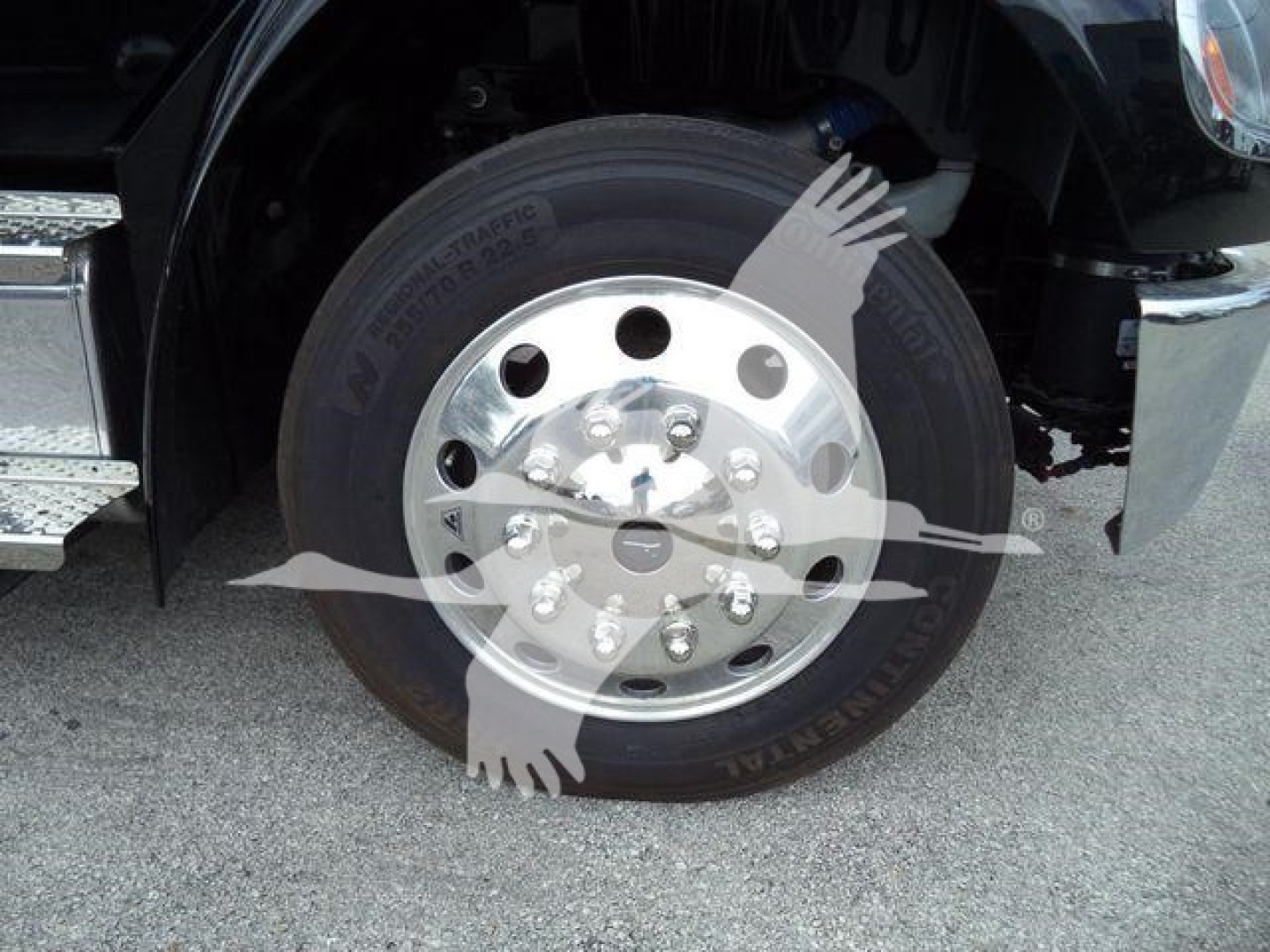 Freightliner M2 106 front wheel showing tire and polished aluminum rim with bolts. Visible text on tire reads 'A/R???' and '...'.