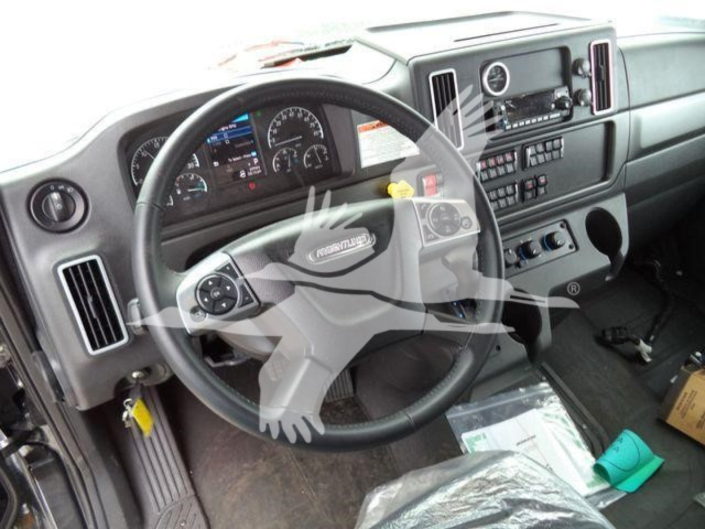 Truck interior showing steering wheel and instrument cluster of a Freightliner M2 106 cab with dashboard controls.