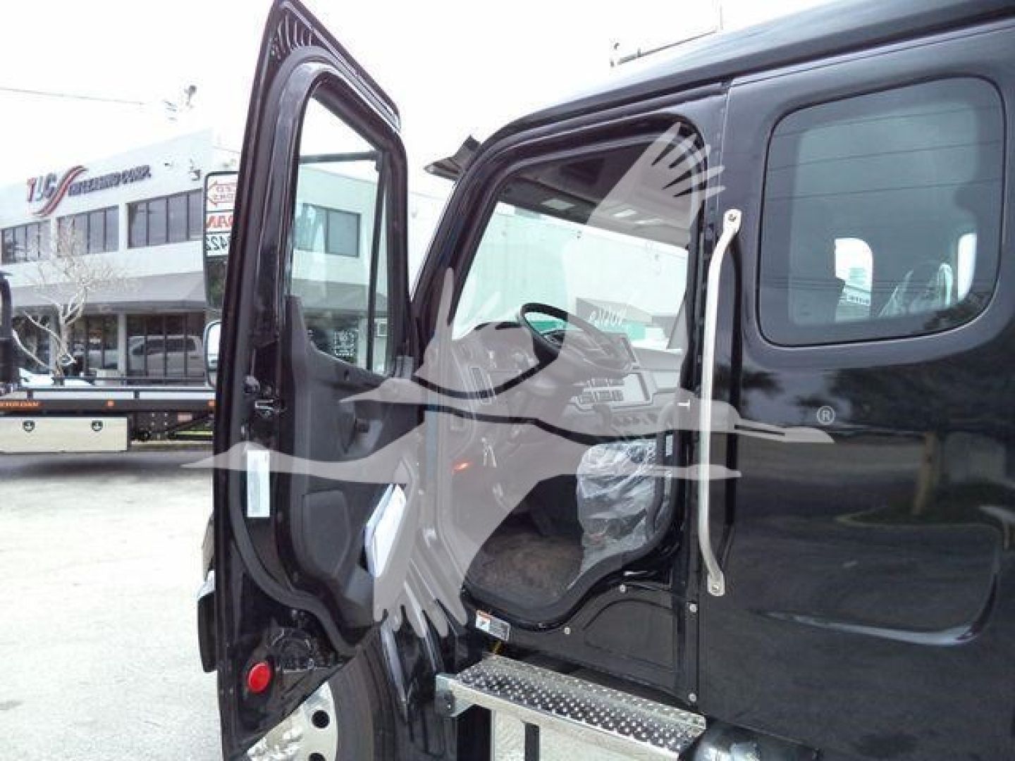 Truck cab with open door showing interior, Freightliner M2 106 series pickup, step plate visible, glossy black exterior, window and door details.