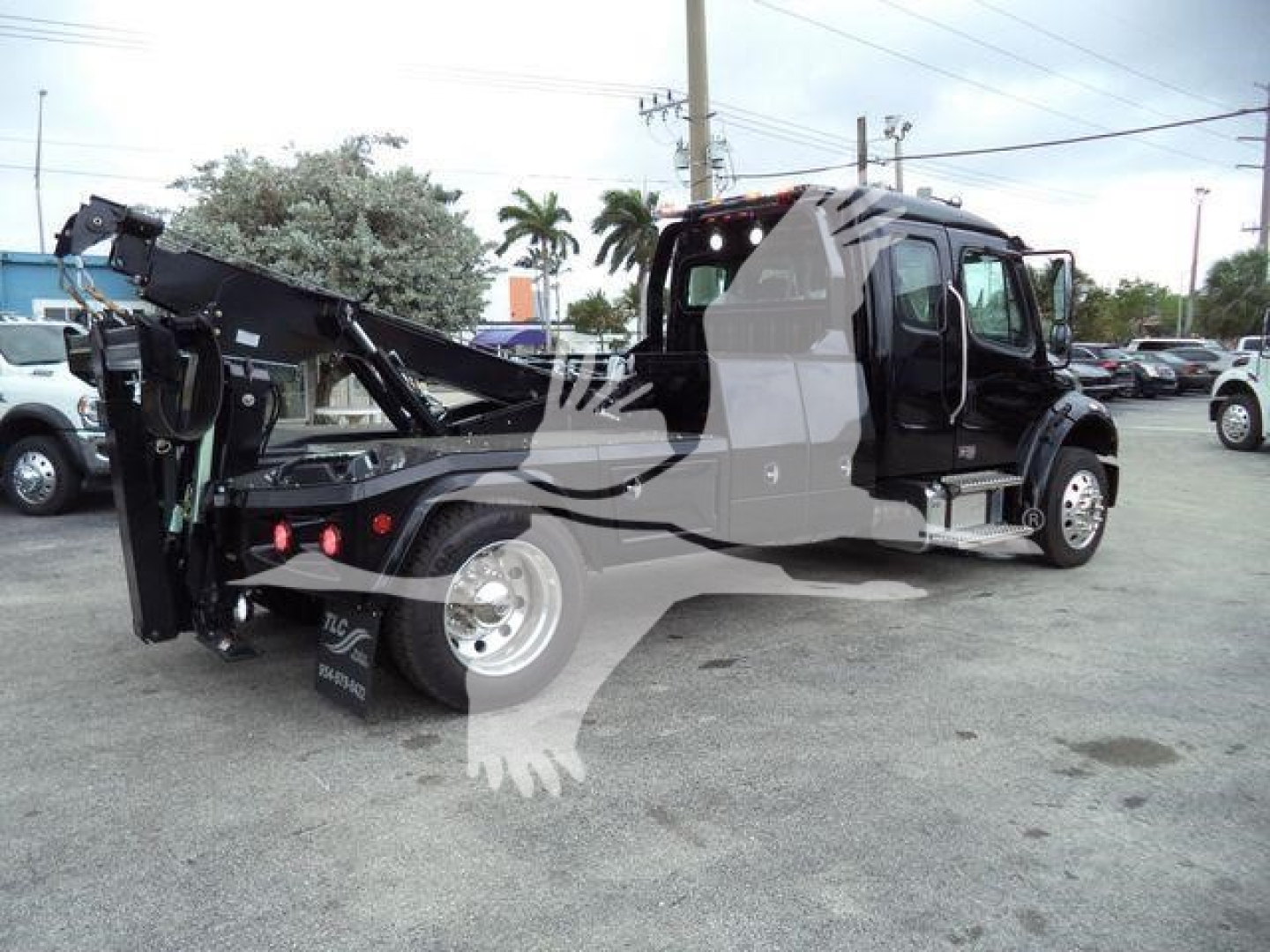 Freightliner M2 106 truck with a mounted winch system and folded crane arm, side view showing cab and chassis.