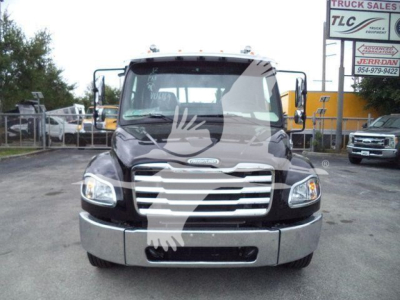 Freightliner M2 106 truck front view showing chrome grille, headlights, and bumper in a dealership lot.