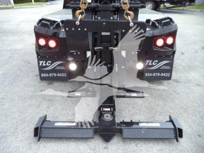Rear view of a Freightliner M2 106 with a winch assembly and tow hooks; two taillights visible, and a heavy-duty hitch/receiver with stabilizing ramps on the ground.