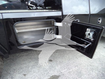 Truck side storage compartment with open door showing empty rectangular cavity and latch; Freightliner M2 106 exterior panels visible.