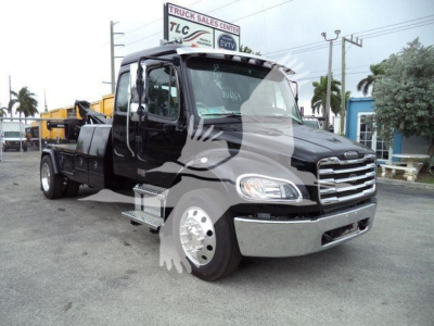 Freightliner M2 106 truck with black cab and chrome front bumper, winch-equipped chassis visible in lot.