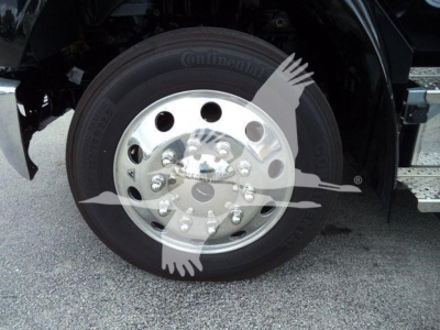 Wheel of a Freightliner truck showing a Continental tire and polished aluminum rim with lug nuts; part of the front wheel well and step visible.