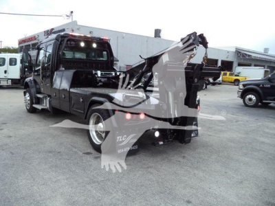 Truck rear view of a Freightliner M2 106 with a crane/winch setup, visible branding on side panels, and multiple warning decals.