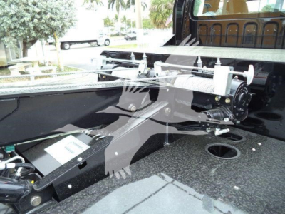Winch system mounted on truck bed showing winch drum, mounting rails, and control housing with hydraulic line connections.
