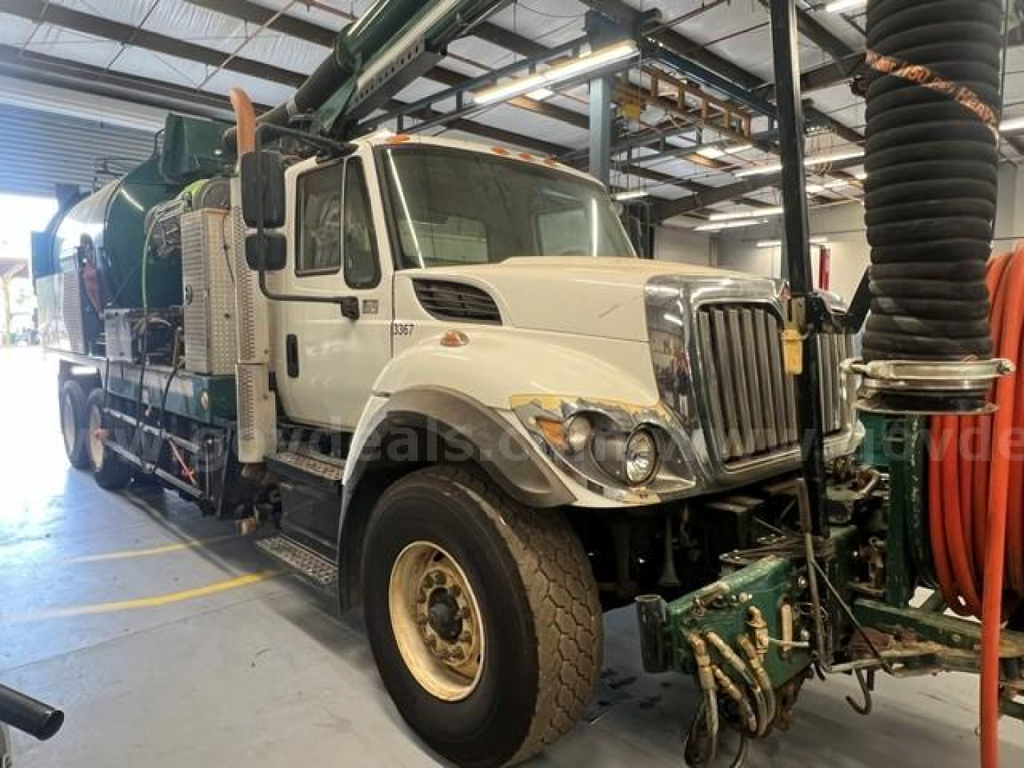 International 7500 vacuum truck in service bay showing cab and side equipment with hoses and machinery mounted behind.