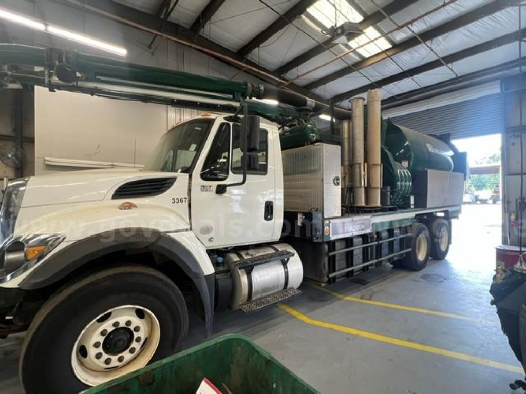 Trucks show a large vacuum tanker mounted on a white International truck chassis, inside a workshop. Visible text includes stock number 706-687 on cab door and the number 3367 near the front.