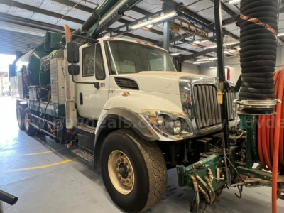 International 7500 vacuum truck in service bay showing cab and side equipment with hoses and machinery mounted behind.