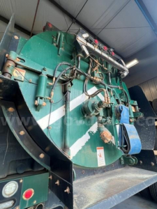 Industrial vacuum truck tank showing green circular tank with hoses and gauges in-service.