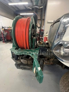 Vacuum truck mounting with large orange reel, hose, and green hose reel cart adjacent to International 7500 front end.