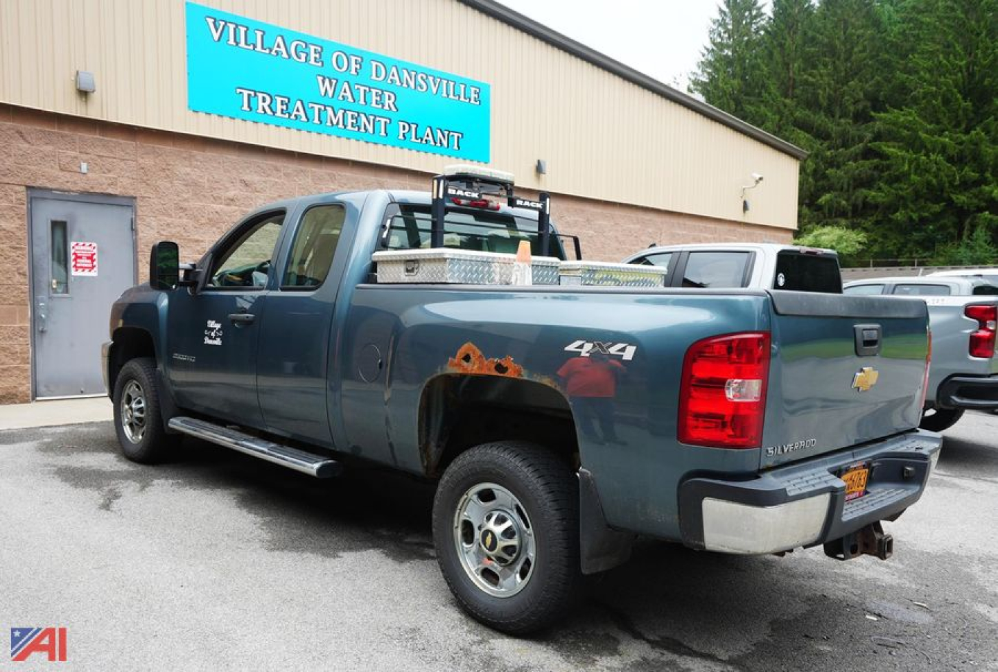 Chevrolet Silverado 2500HD extended cab pickup with plow and 4x4 badge visible in rear, blue paint with rust patches near bed and chrome bumper.