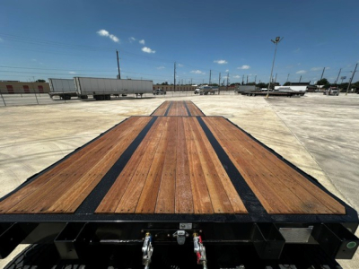 Flatbed trailer deck with wooden planks and black steel frame; photo taken from rear towards cab area, visible long platform and support beams