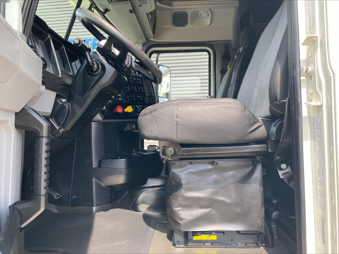 Truck cab interior of a 2020 Mack Anthem showing steering wheel, dashboard, and driver seat with base cover.