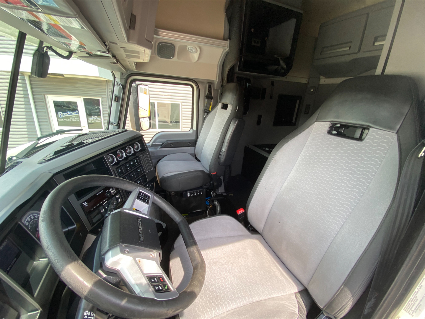 Truck cab interior of a 2020 Mack Anthem showing steering wheel, driver's seat, dashboard with gauges, and passenger seat.