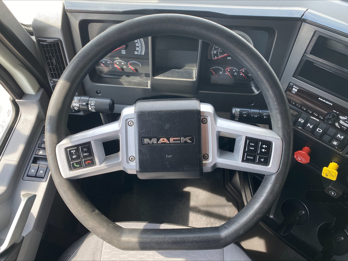 Steering wheel and dashboard of a Mack ANTHEM truck cab showing MACK emblem and control stalks.