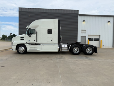 Truck cab and chassis of a 2020 Mack Anthem semi-truck, white with sleeper cab, side view showing dual rear axles and fifth-wheel area.