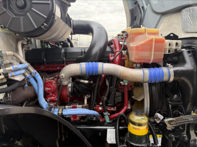 Engine bay of a 2020 Mack Anthem sleeper cab showing hoses, coolant reservoir, and yellow oil/filter canister with blue clamps.