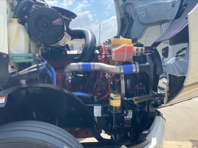 Engine bay of a 2020 Mack Anthem showing coolant reservoir, yellow dipstick, hoses, and various metal components.