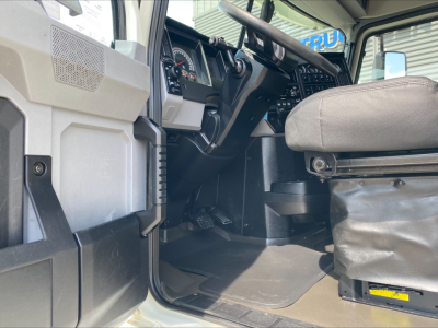 Mack ANTHEM truck cab interior showing steering wheel, dashboard, and entry area with driver seat and floor mats.