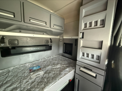 Truck sleeper cab interior showing bunk bed with storage cabinets and control panels in a Mack ANTHEM truck cabin interior.