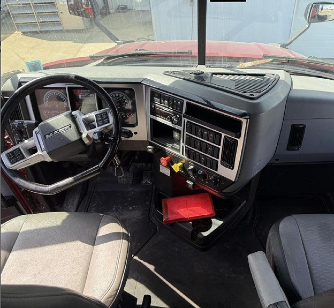 Truck cab interior showing steering wheel and dashboard of a 2020 Mack Anthem with exposed gear levers and center console.