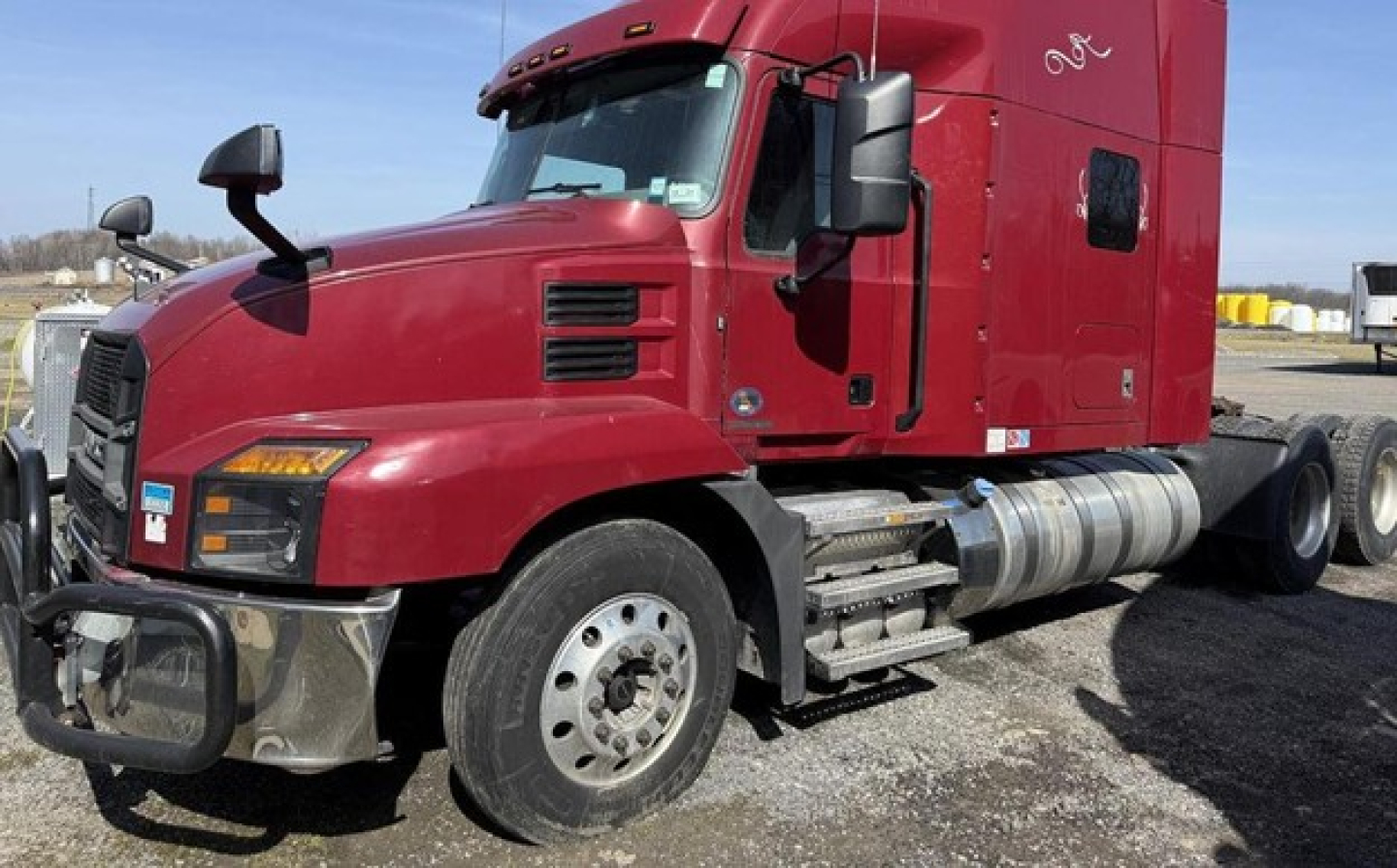 Truck: red 2020 Mack Anthem conventional sleeper tractor shown from front-left side with sleeper cab, fuel tanks, and front bumper.