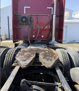 Truck rear view showing fifth wheel plate and drivetrain on a Mack Anthem tractor, with mud and wear marks on the plate area.