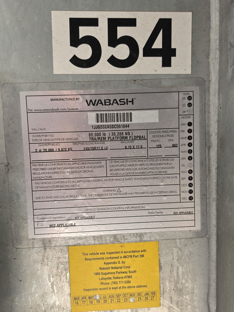 Wabash trailer identification plate with serial/ VIN label and large number 554 above it, showing Manufacturer: WABASH and detailed specifications on the metal plate.