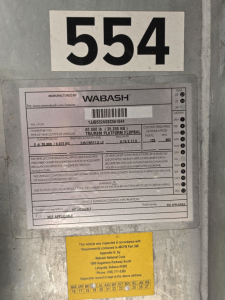 Wabash trailer identification plate with serial/ VIN label and large number 554 above it, showing Manufacturer: WABASH and detailed specifications on the metal plate.