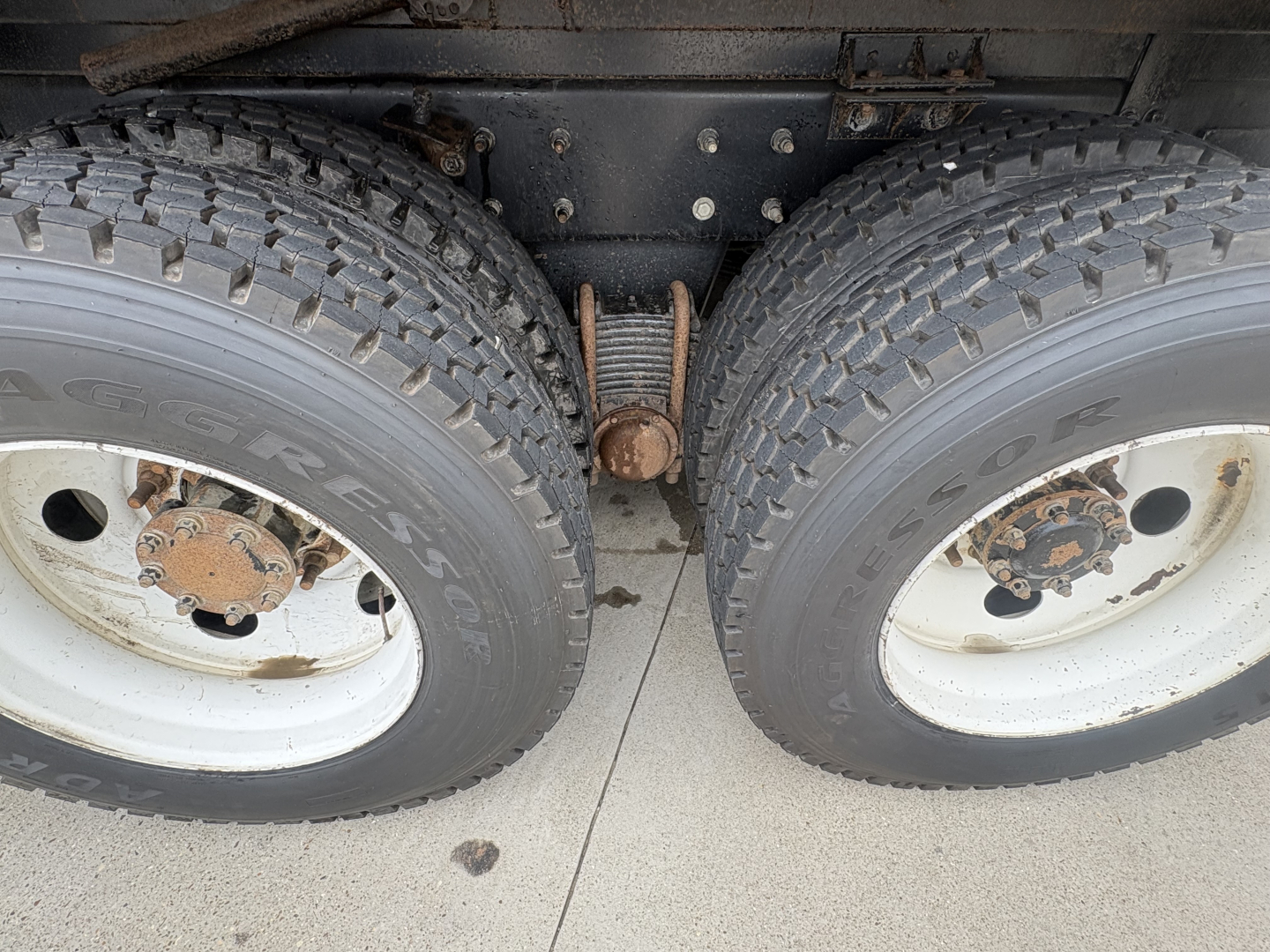 Two rear truck wheels with dual tires and a leaf spring suspension visible between them.