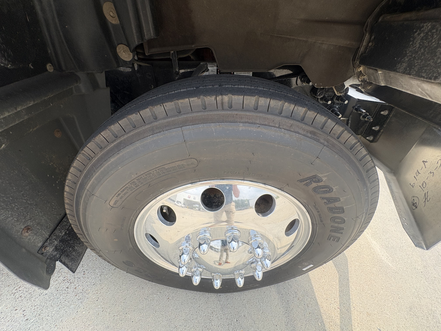 Wheel and tire close-up on Mack GR64F dump truck showing steel wheel with chrome lug nuts and tread pattern.
