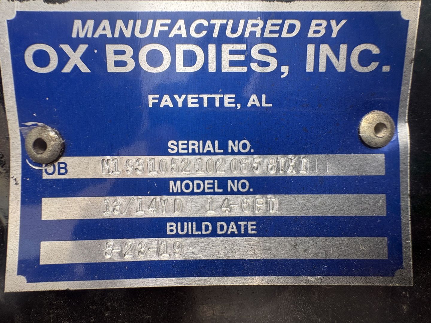 Blue OEM plate reading Manufactured by OX Bodies, Inc. Fayette, AL with serial number and model/build date fields visible.