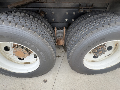 Two rear truck wheels with dual tires and a leaf spring suspension visible between them.
