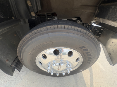 Wheel and tire close-up on Mack GR64F dump truck showing steel wheel with chrome lug nuts and tread pattern.