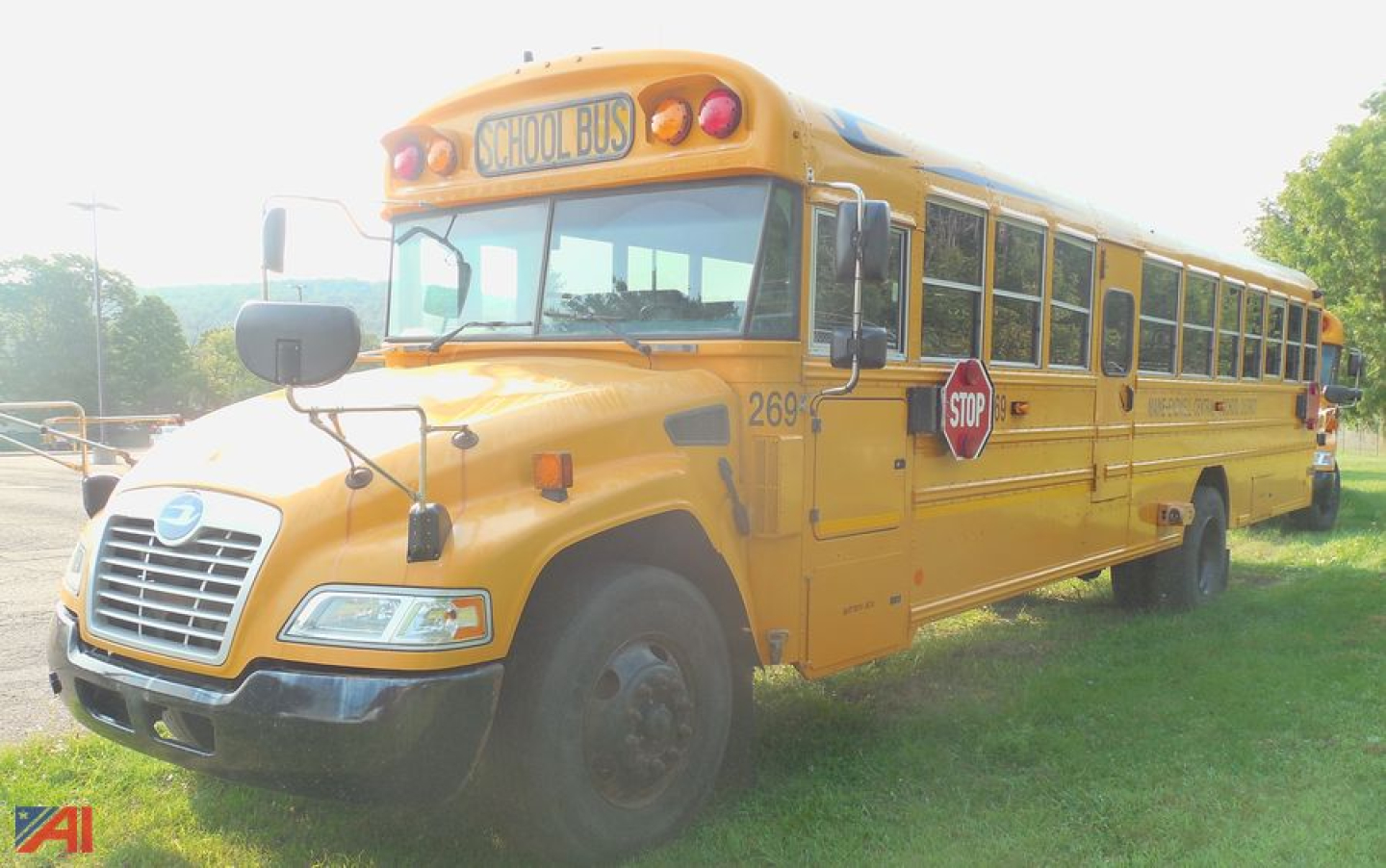 Yellow school bus with stop sign extended and 'SCHOOL BUS' sign on top showing side view and front grille.