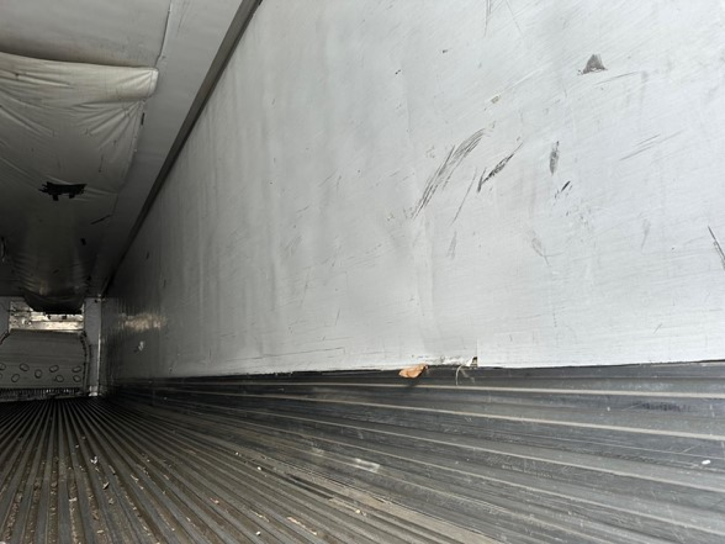 Utility 3000R trailer interior side wall and ribbed floor with scuff marks and wear visible.