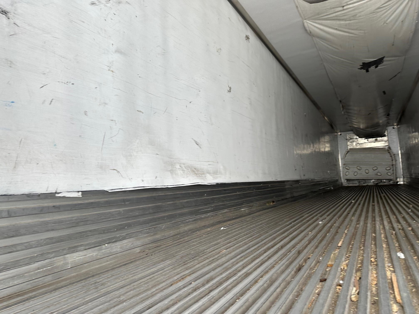 Storage trailer interior showing ribbed steel floor and aluminum sidewall; empty cargo area of a 2013 Utility 3000R trailer.