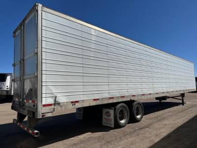 Trailer side view showing large rectangular storage trailer with tandem axles and white reflective tape.
