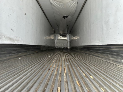 Interior of a Utility trailer showing ribbed metal floor and white side walls; perspective from rear toward front with light at far end.